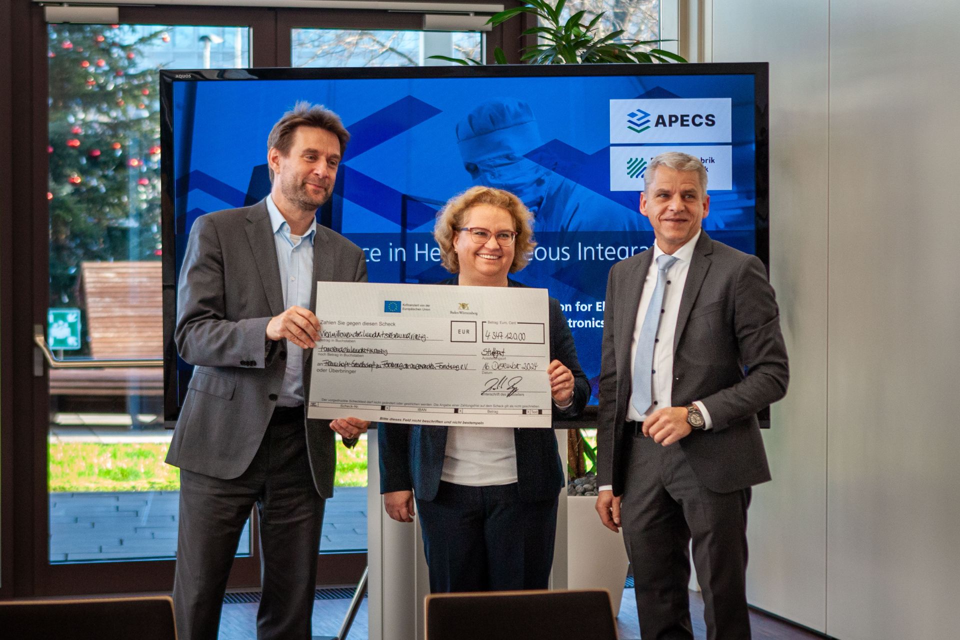 Visit STS Dr. Rapp APECS 3 State Secretary Dr. Patrick Rapp passes the Fraunhofer IAF Institute Management the cheque for the APECS funding.